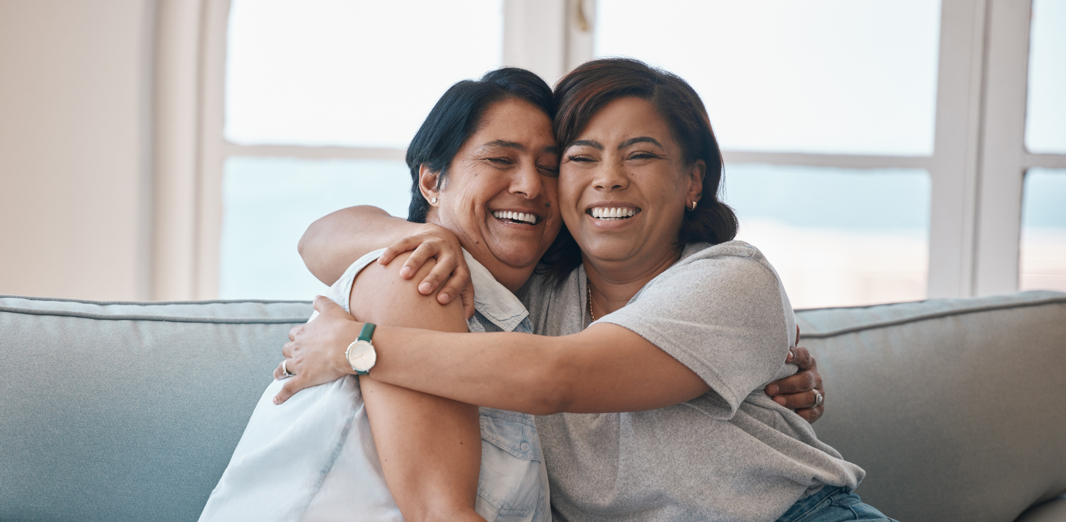 Two women hugging each other on couch