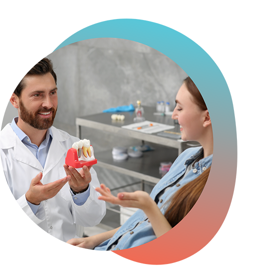 Male dental patient holding dental implant model in front of female patient