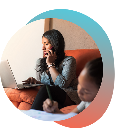 Woman sitting on couch working on laptop and talking on phone