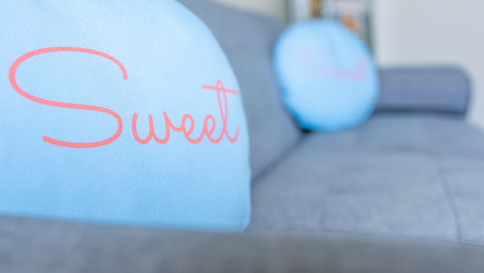 Close up of pillow on couch with the word Sweet on it