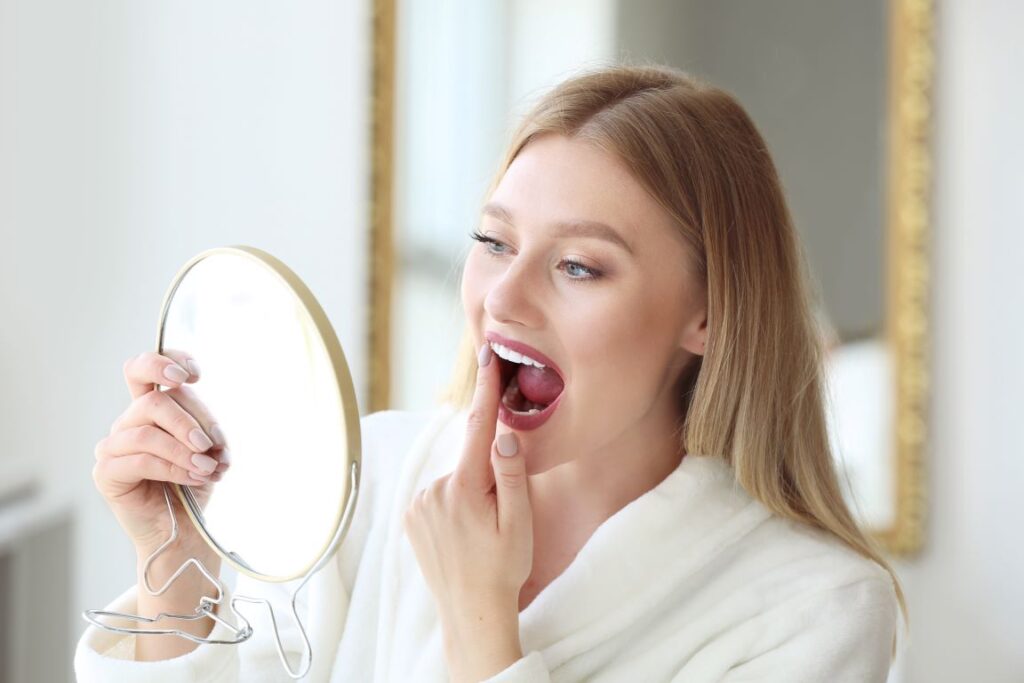 A woman looking at her loose tooth in the mirror.