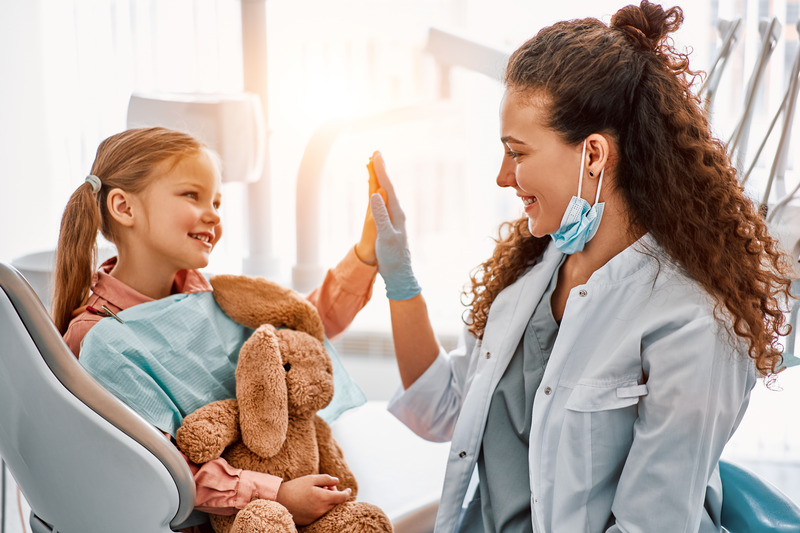 Child with good dental health high-fiving dentist